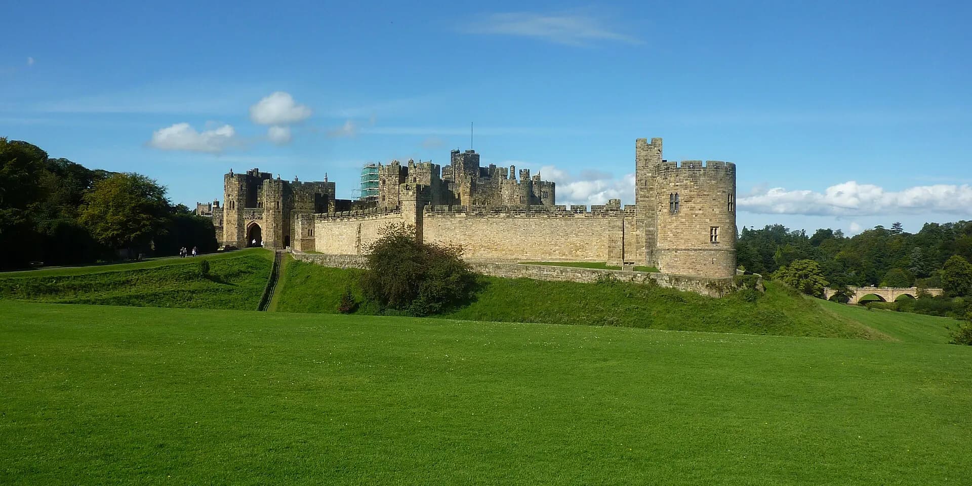 Alnwick Castle's long stone walls and towers above a wide green lawn