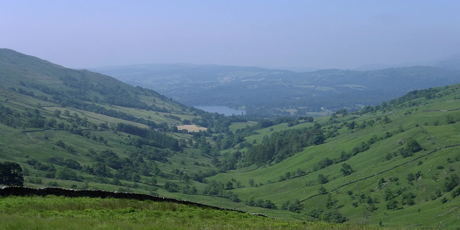 Green fells and a valley falling away towards Ambleside and Windermere, seen from near Kirkstone Pass