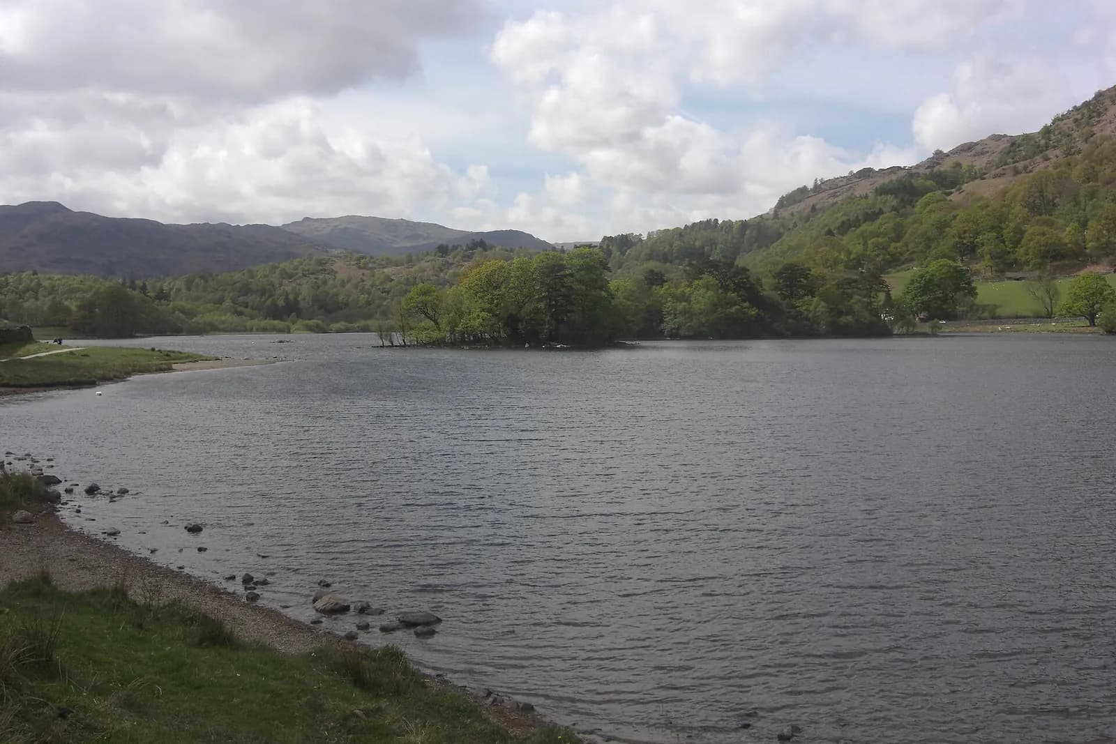 Rydal Water with its small wooded island, below green fells