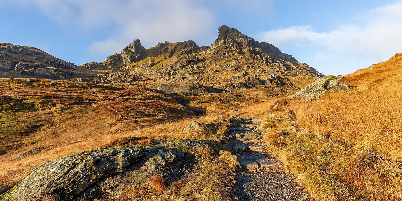 The jagged rocky peaks of The Cobbler above golden autumn moorland
