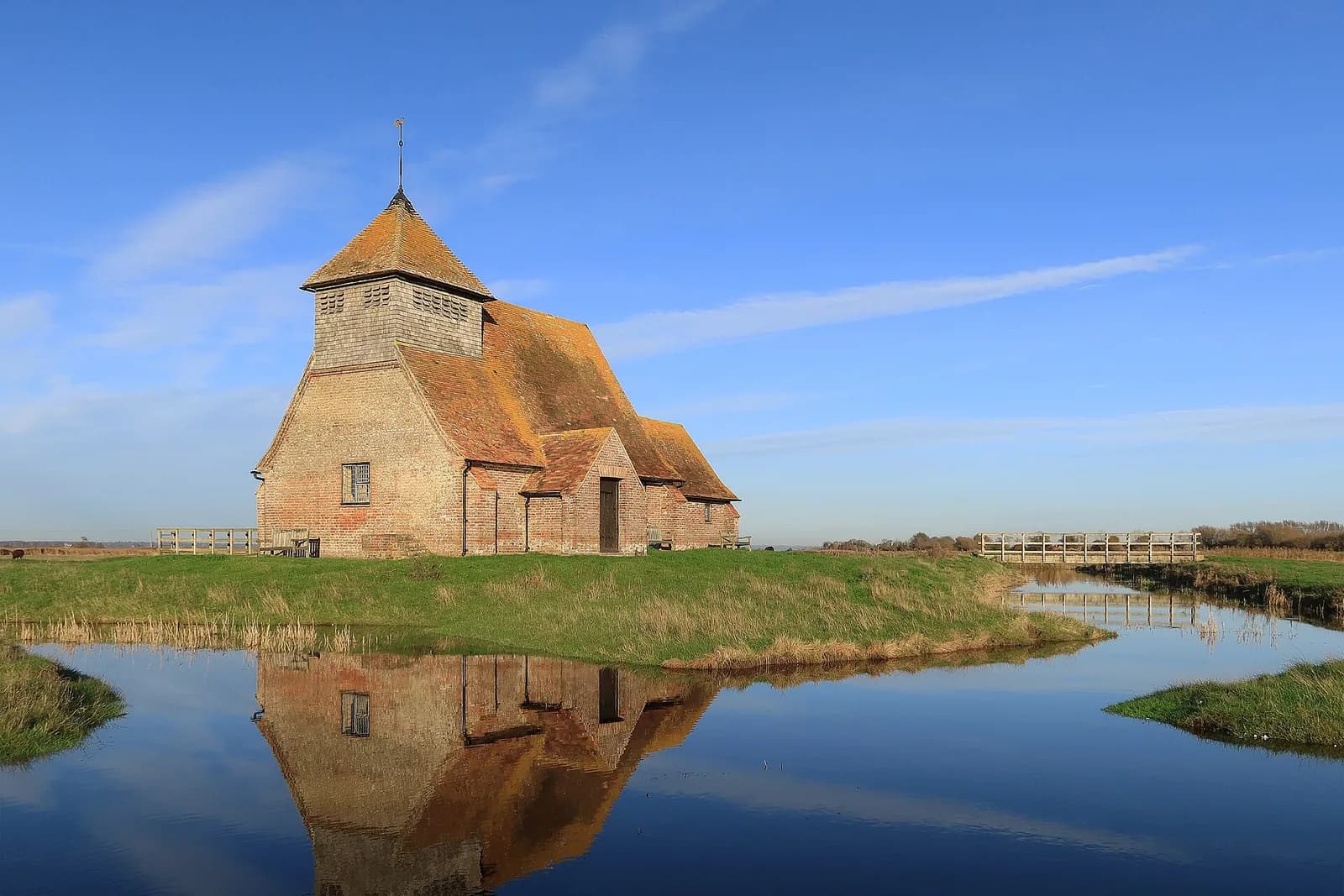 The little church of St Thomas Becket at Fairfield, standing alone on Romney Marsh, reflected in water