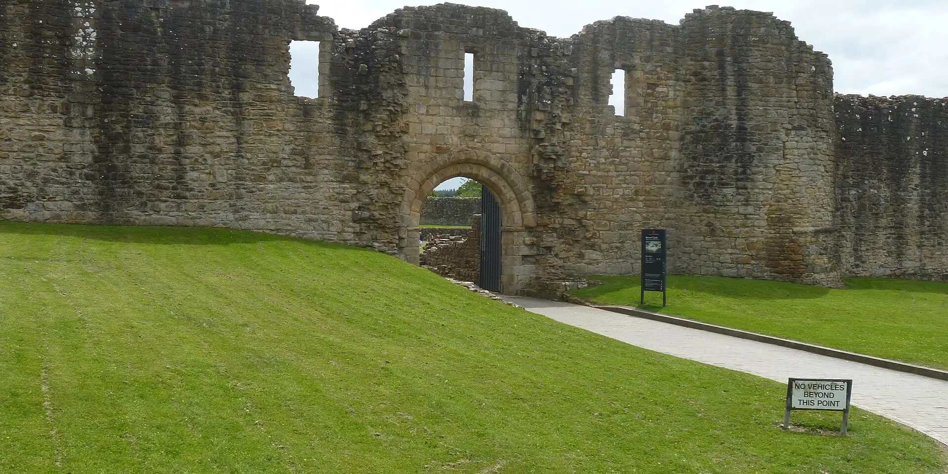 The ruined stone walls and gateway of the castle at Barnard Castle, above a green lawn