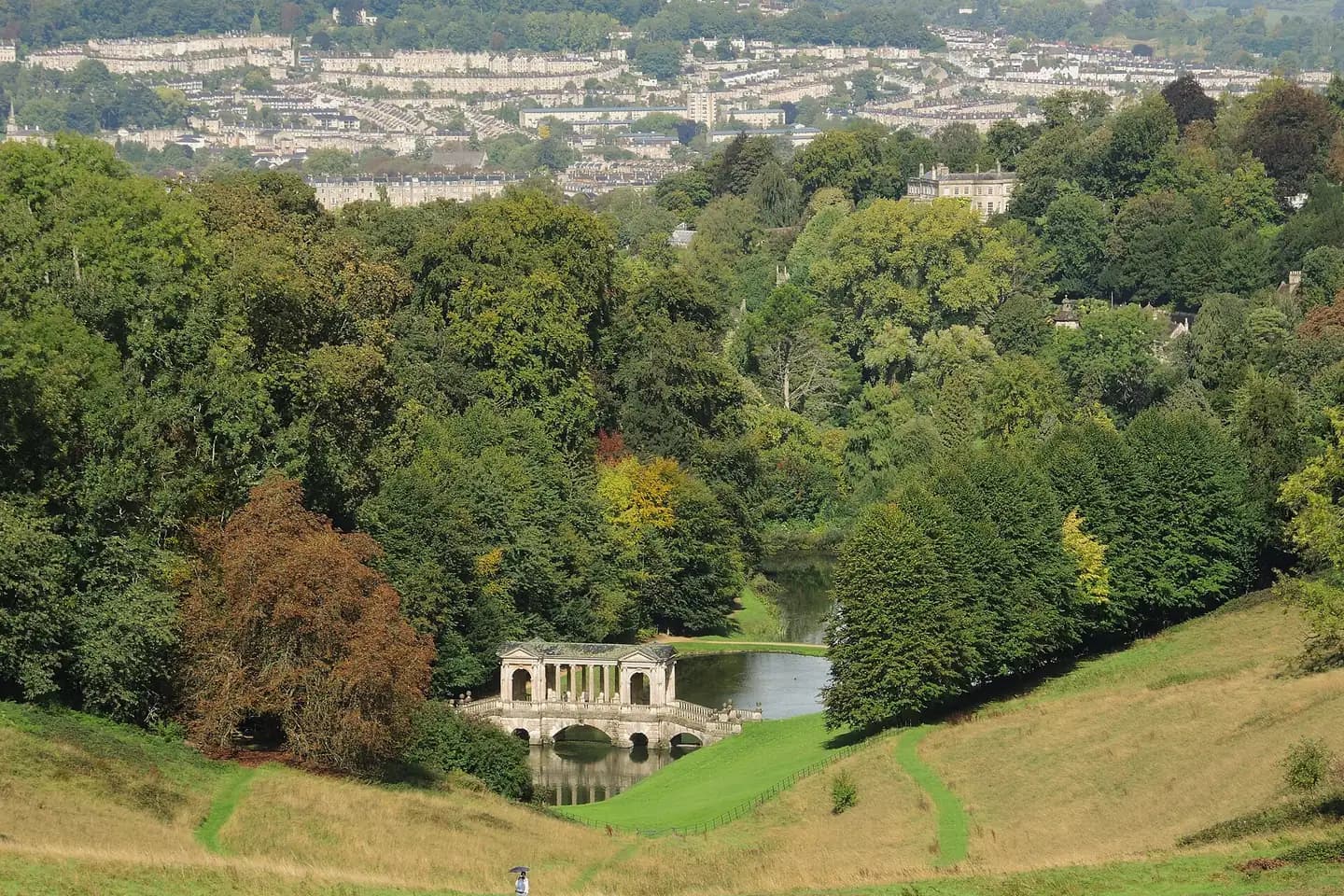 The Palladian Bridge at Prior Park in a wooded valley, with the city of Bath on the hills beyond