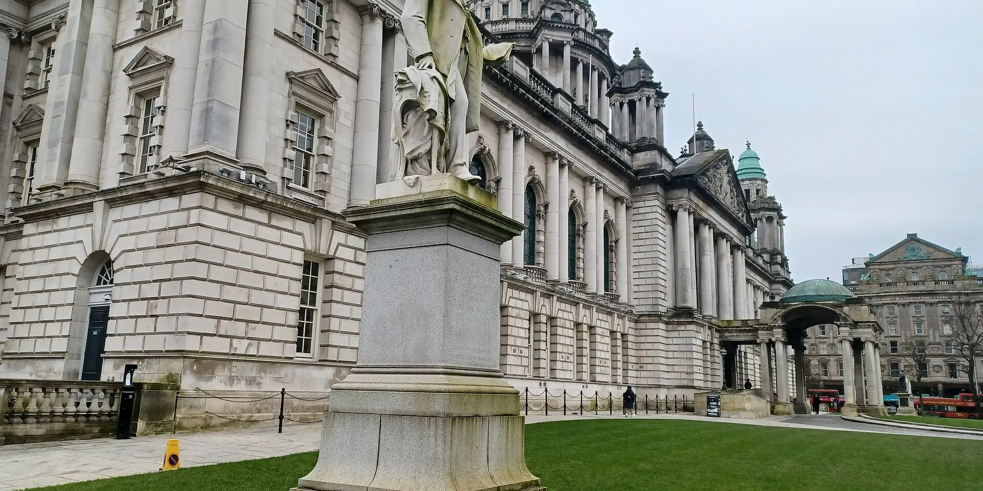 The white stone domes and columns of Belfast City Hall, with a statue on the lawn in front