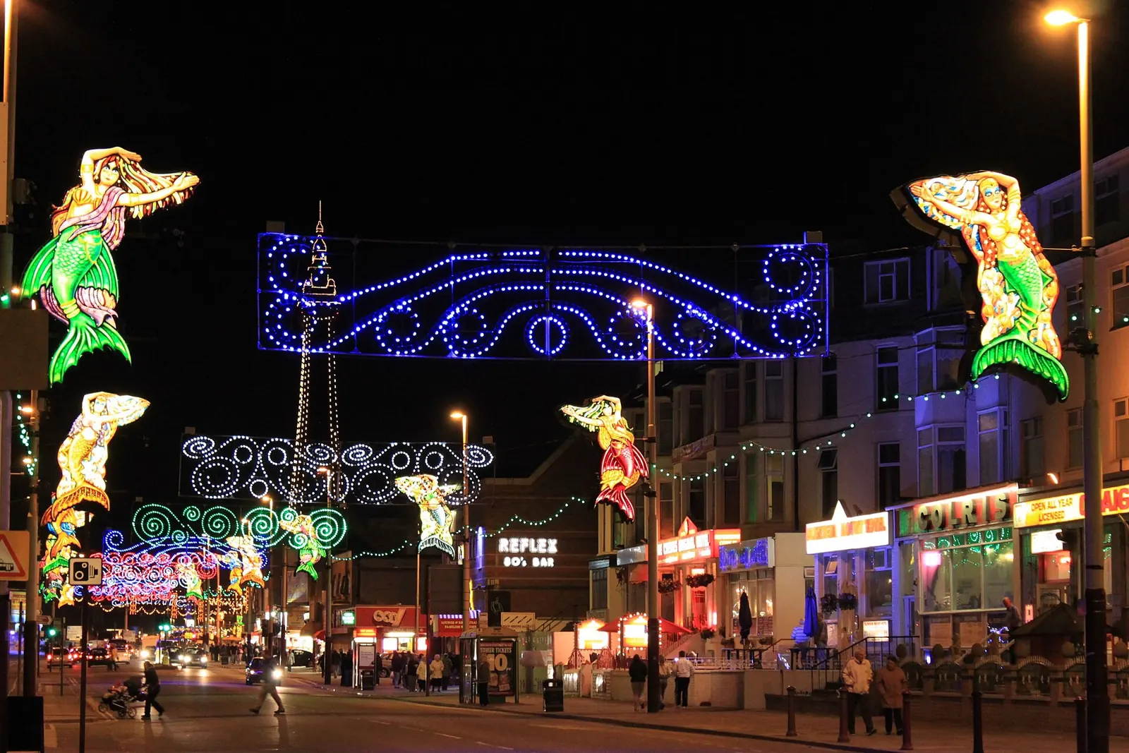 The Illuminations at night: lit mermaids and strings of lights across a street