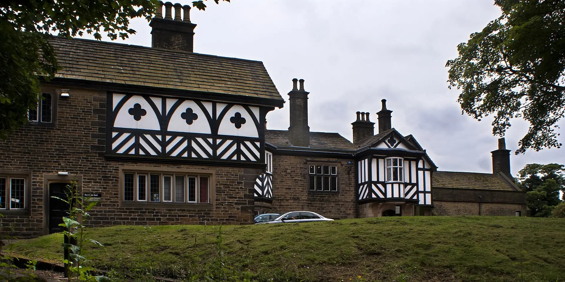 Smithills Hall, an old manor house with black-and-white timbered gables, behind a lawn