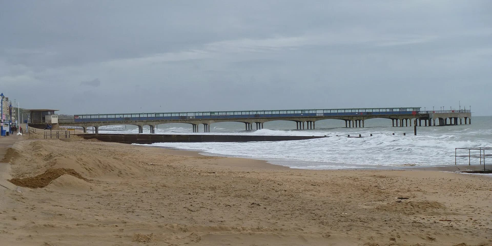 Boscombe Pier stretching out over the sea from a sandy beach on a grey day