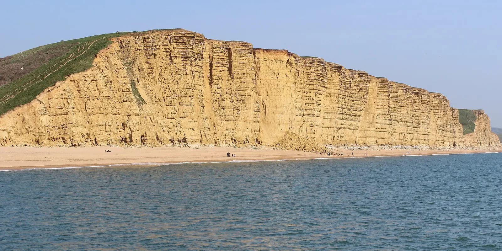 The golden sandstone East Cliff at West Bay, rising straight up from the beach and the sea