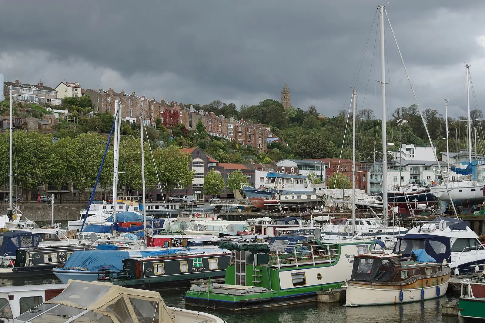 Boats moored in Bristol's Baltic Wharf marina, with the hillside of Cliftonwood behind