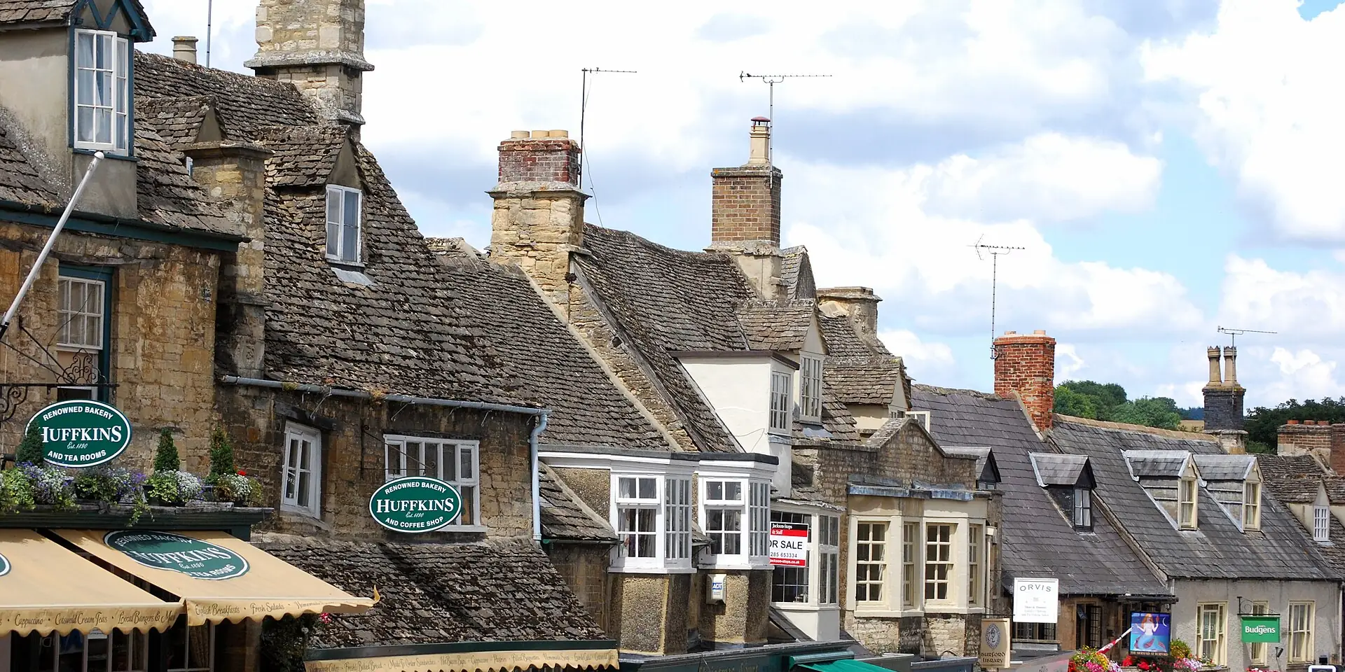 The stone-roofed cottages and shops of Burford High Street, with chimneys against the sky