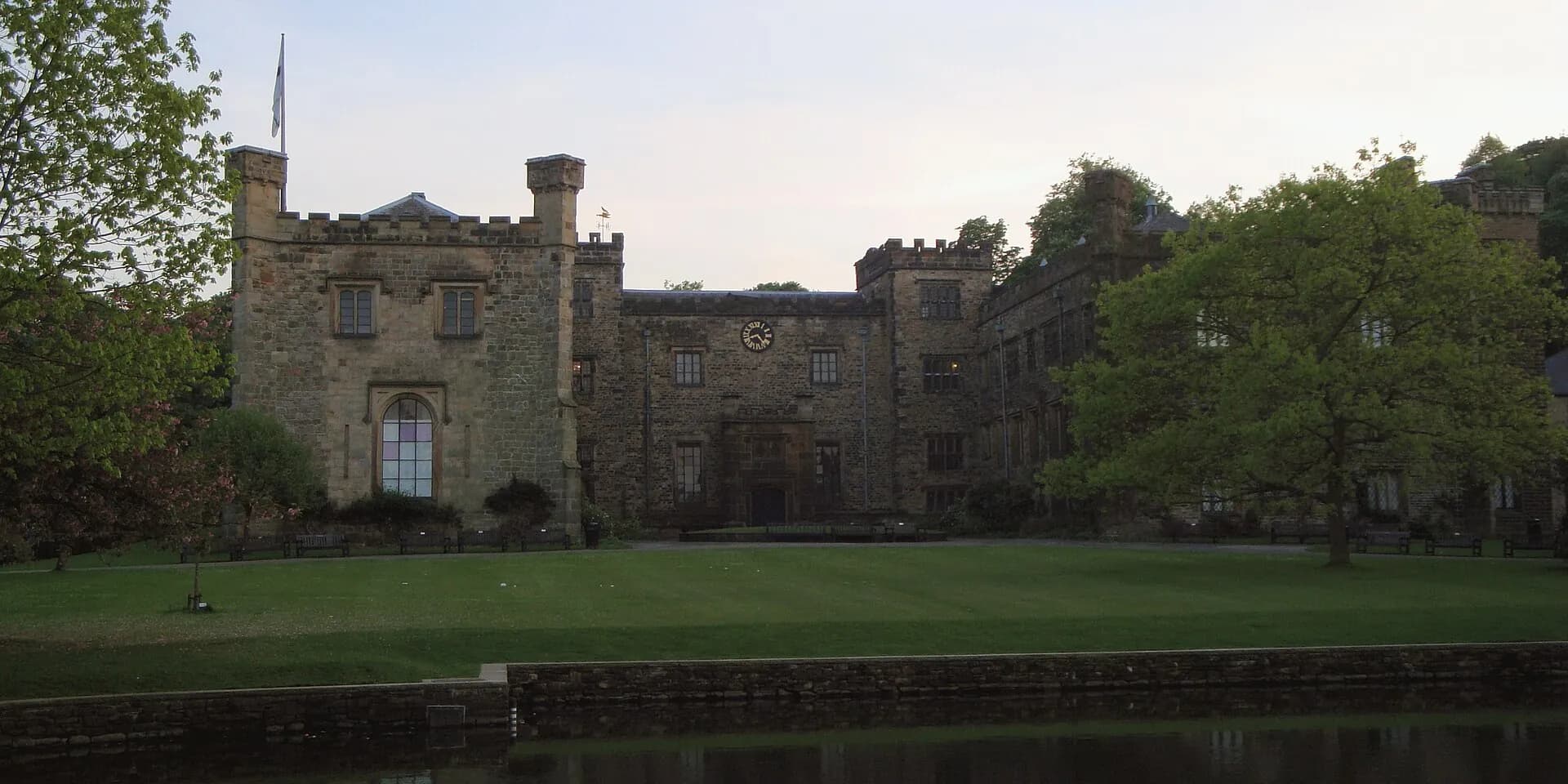 Towneley Hall, a battlemented stone country house behind a lawn and trees