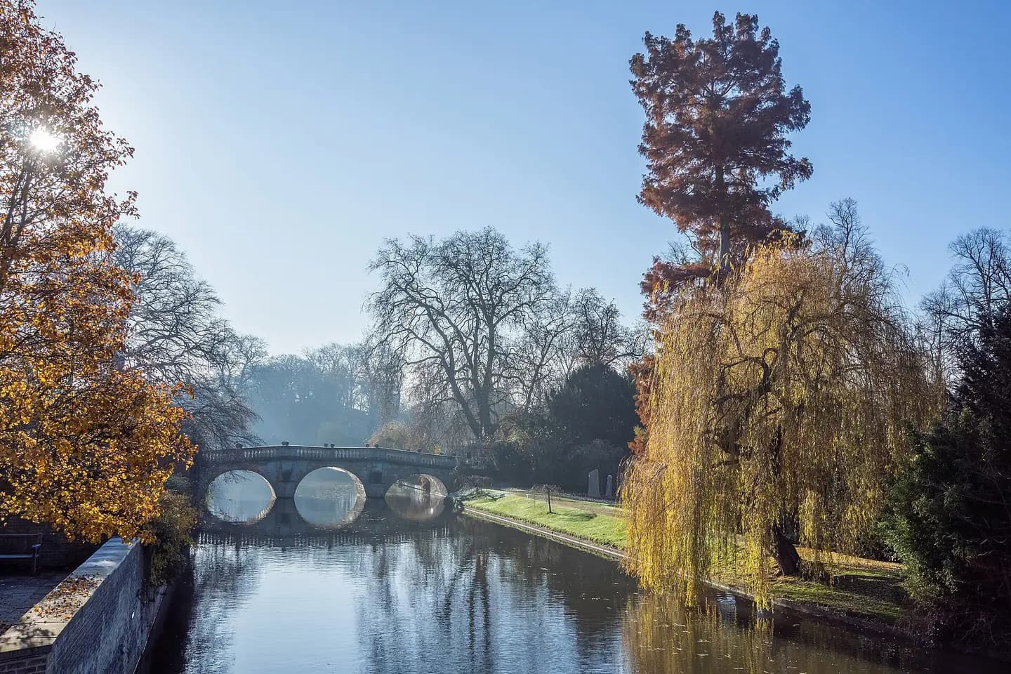 Clare College Bridge over the River Cam on a frosty autumn morning, with willows on the bank
