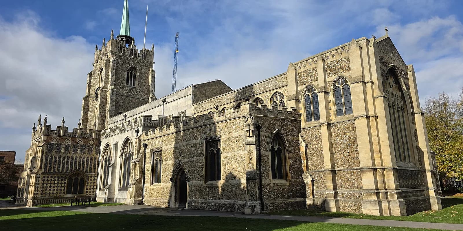 Chelmsford Cathedral's flint tower and spire beside its pale stone nave, on a sunny day