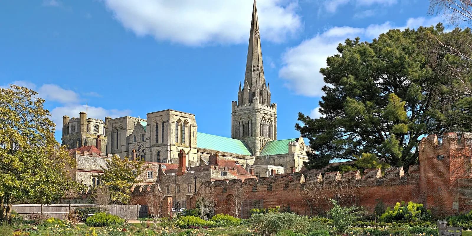 Chichester Cathedral and its tall spire rising above the old city wall and trees