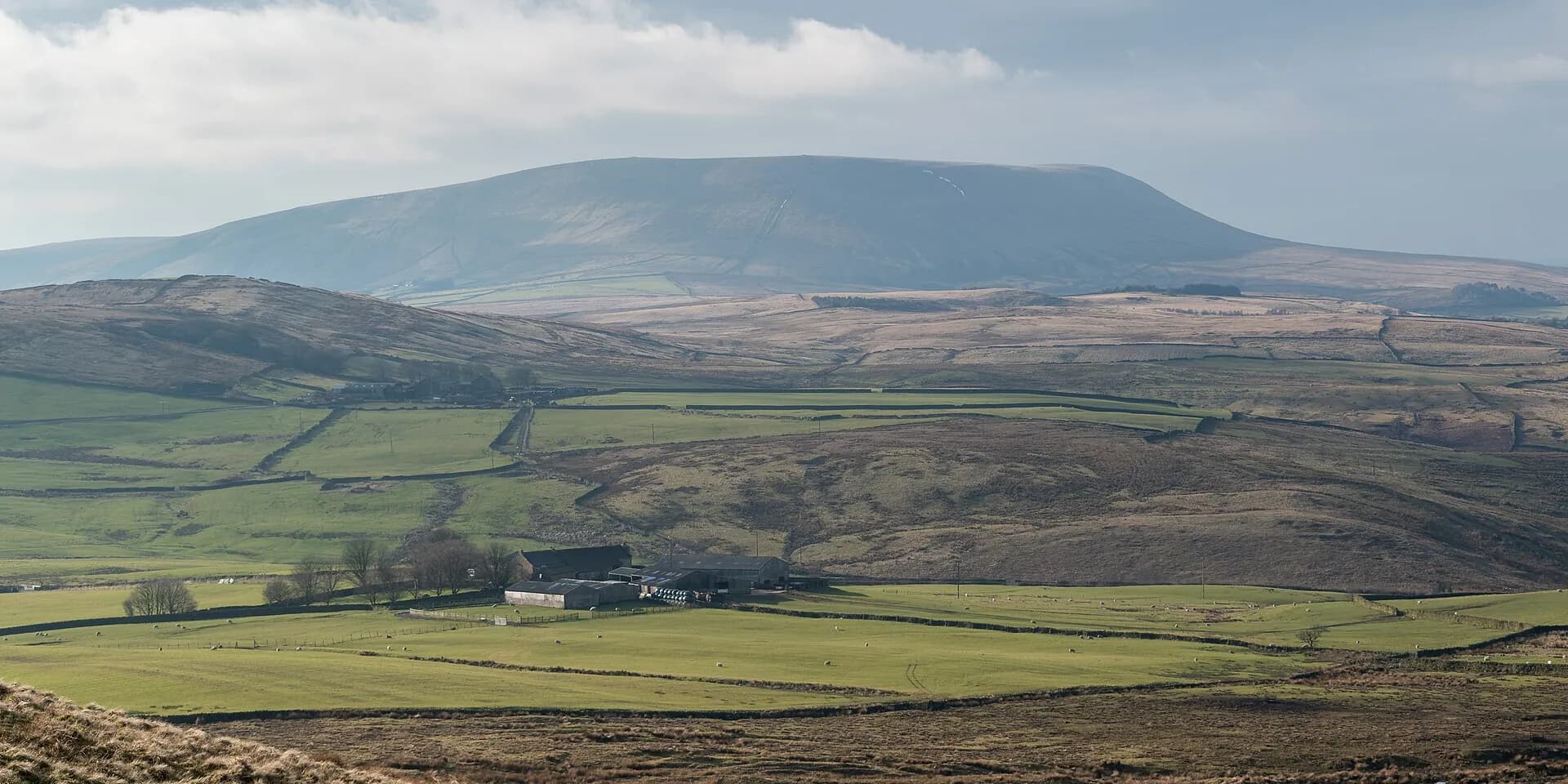 The long flat-topped mass of Pendle Hill above a patchwork of fields and moorland