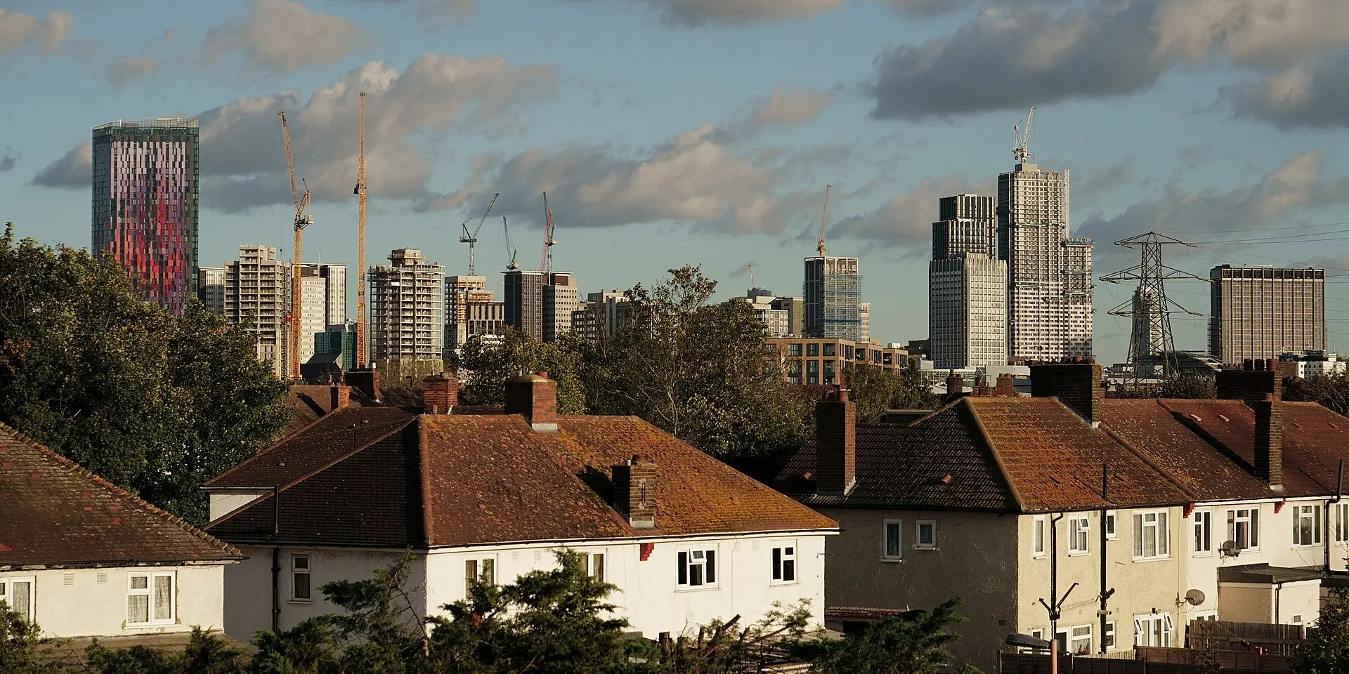 Croydon's tower blocks rising behind a row of suburban houses under a cloudy sky