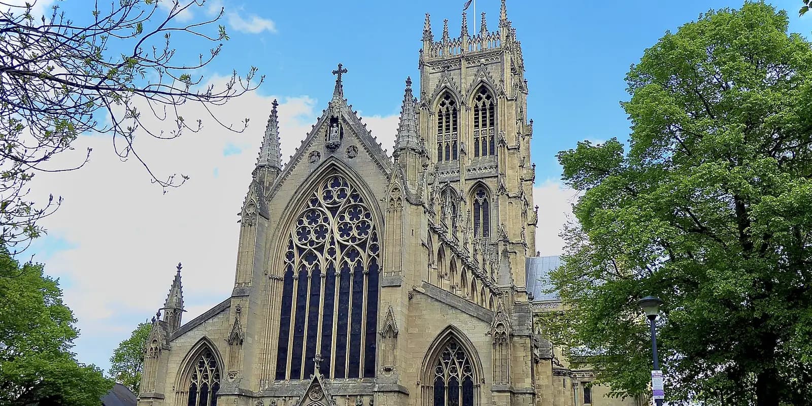 The tall Gothic tower and great window of Doncaster Minster, framed by green trees
