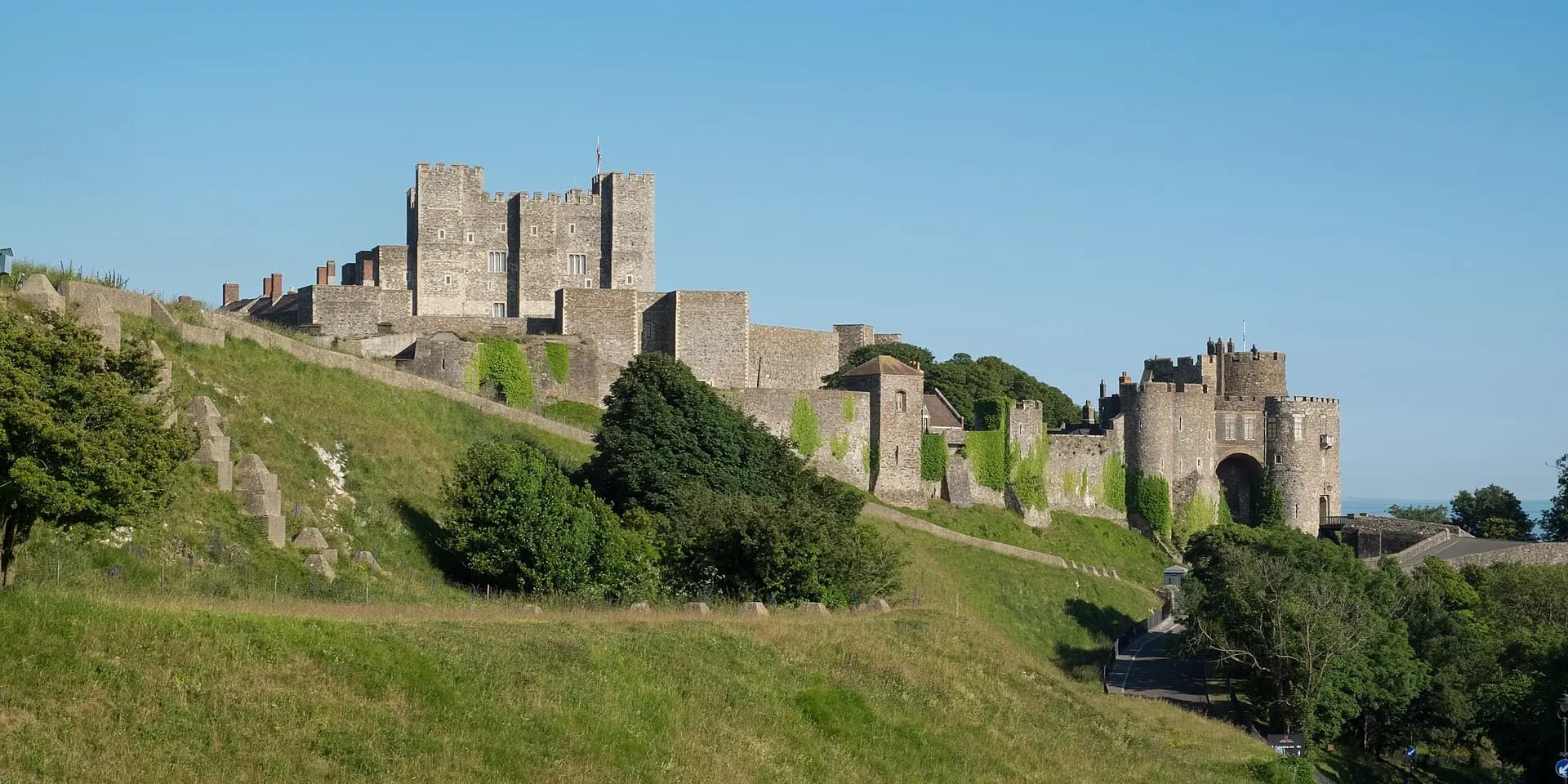 Dover Castle's great keep and walls on a green hillside under a clear blue sky