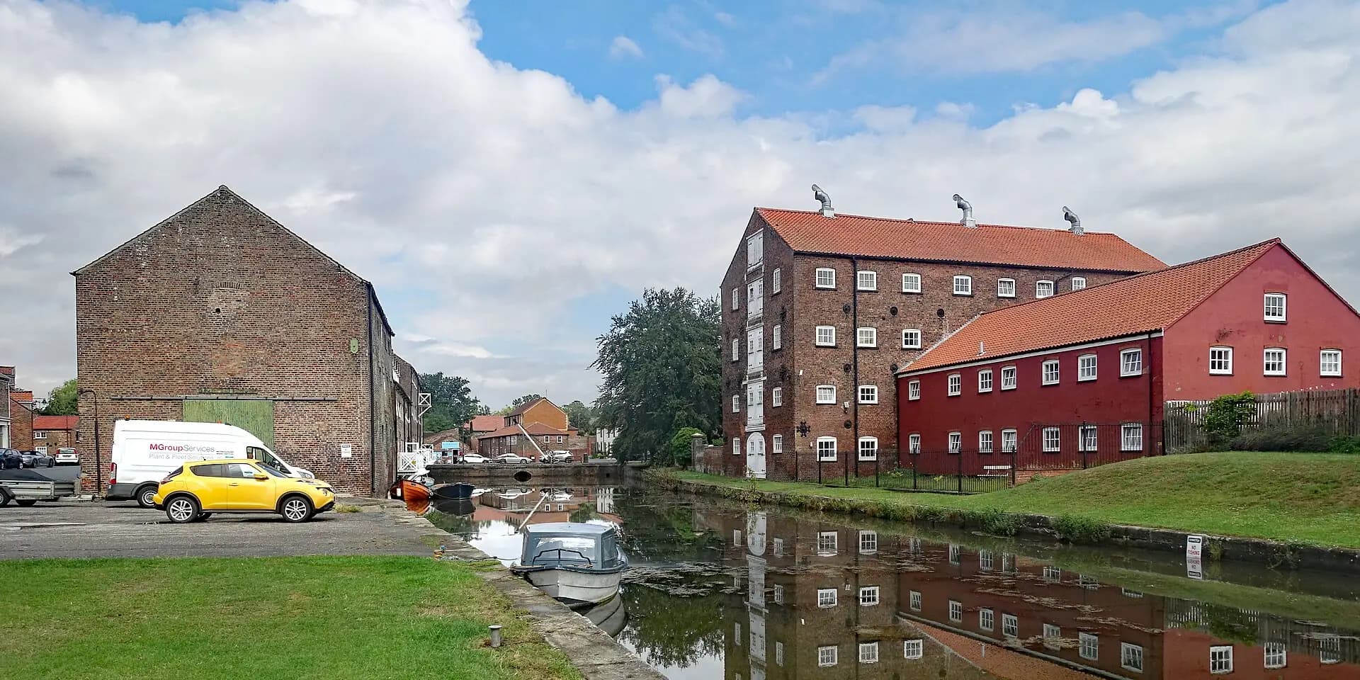 Old brick mill buildings reflected in the water of Driffield Canal Basin