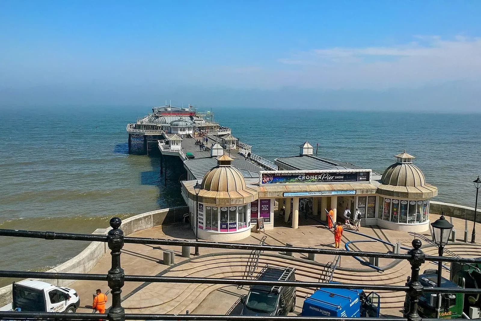 Cromer Pier and its domed pavilion stretching out into a calm blue sea on a summer day