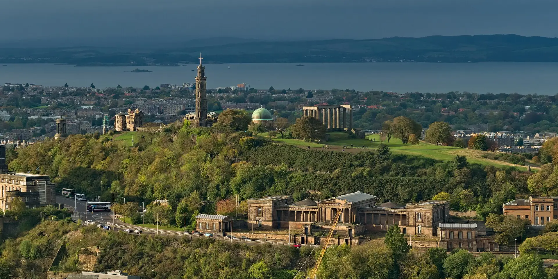 Calton Hill and its monuments above Edinburgh's rooftops, with the Firth of Forth beyond
