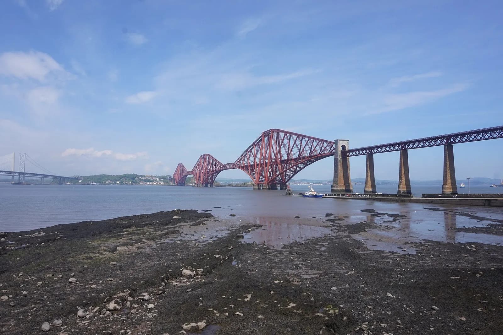 The red cantilevered Forth Bridge stretching across the Firth of Forth from South Queensferry