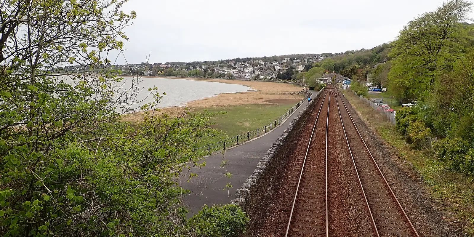 The railway and promenade running beside Morecambe Bay, with the town on the wooded shore beyond