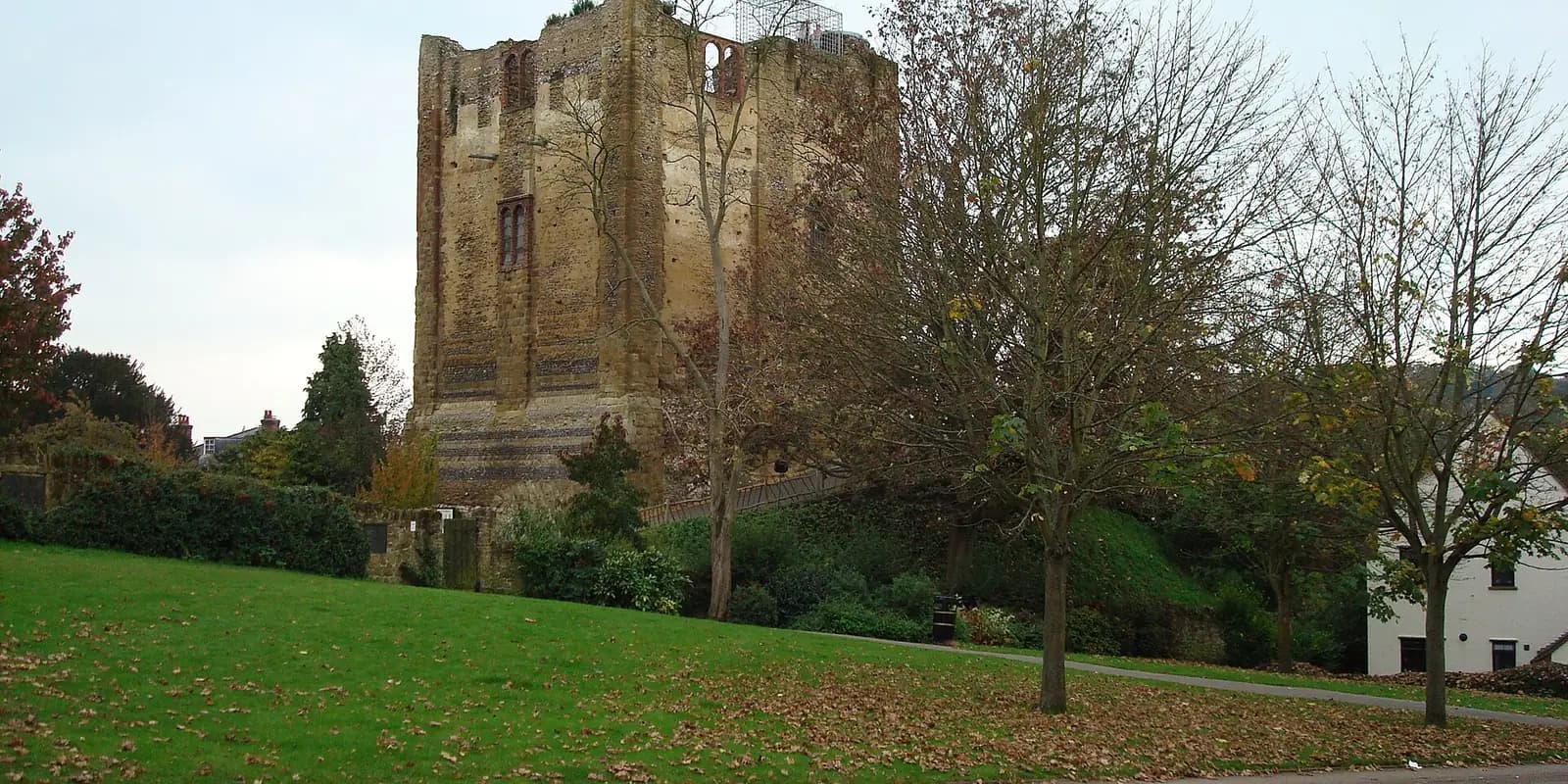 The stone keep of Guildford Castle among trees above a lawn