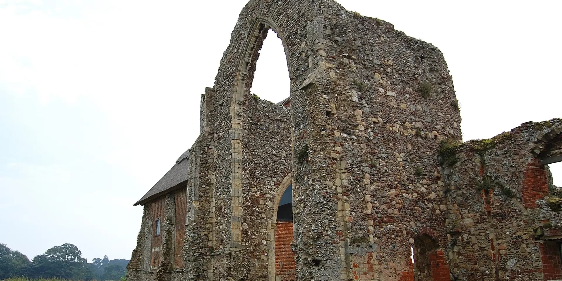 The ruined flint and brick walls of Leiston Abbey, with a tall empty window arch