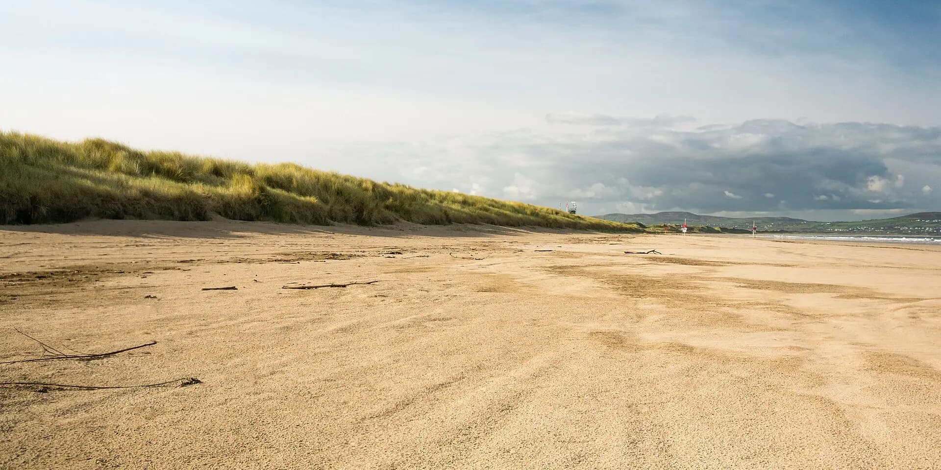 The long empty sands of Benone Strand, backed by grassy dunes