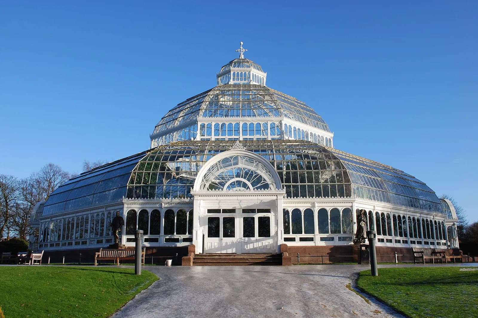 The domed Victorian glasshouse of Sefton Park Palm House under a blue sky