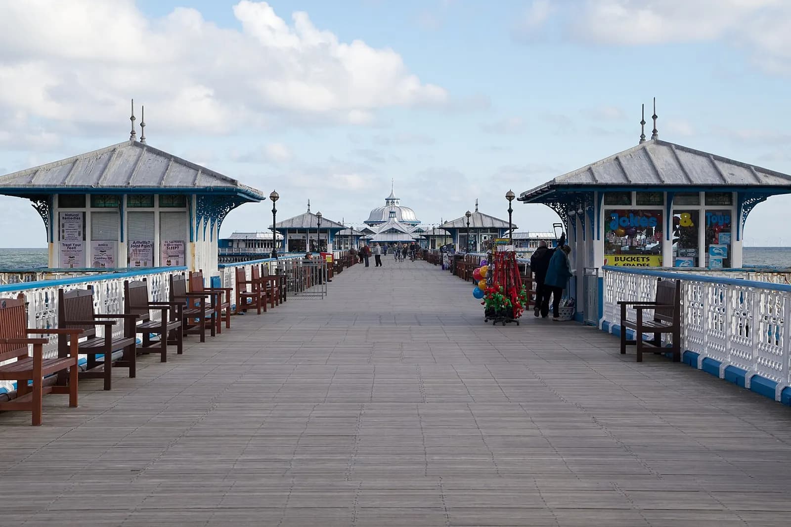 The long wooden deck of Llandudno Pier lined with Victorian kiosks and benches