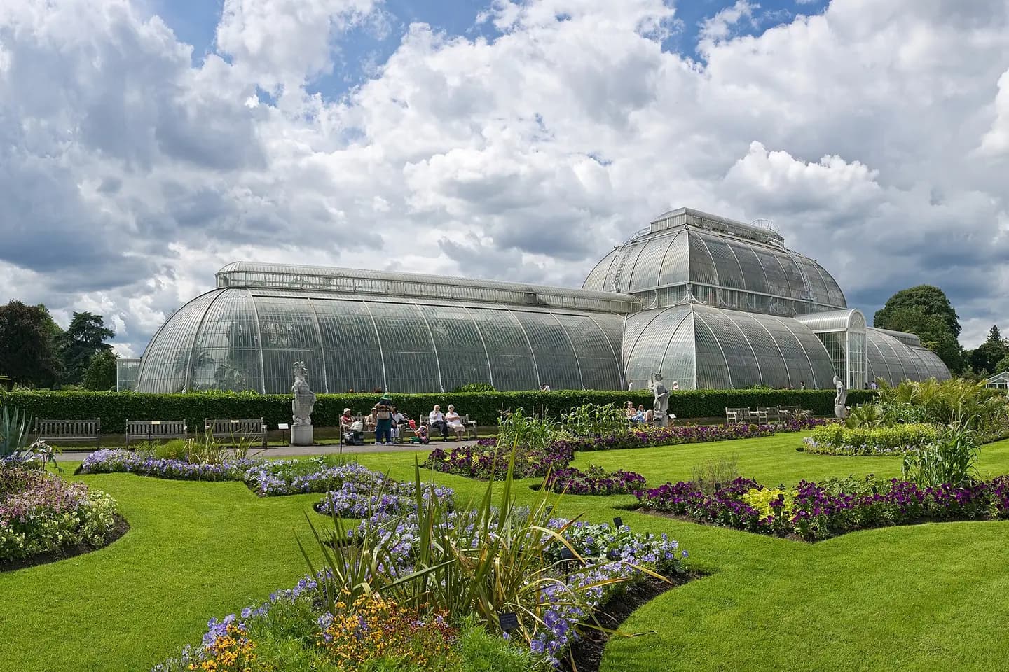 The glass Palm House at Kew Gardens, beyond lawns and flower beds