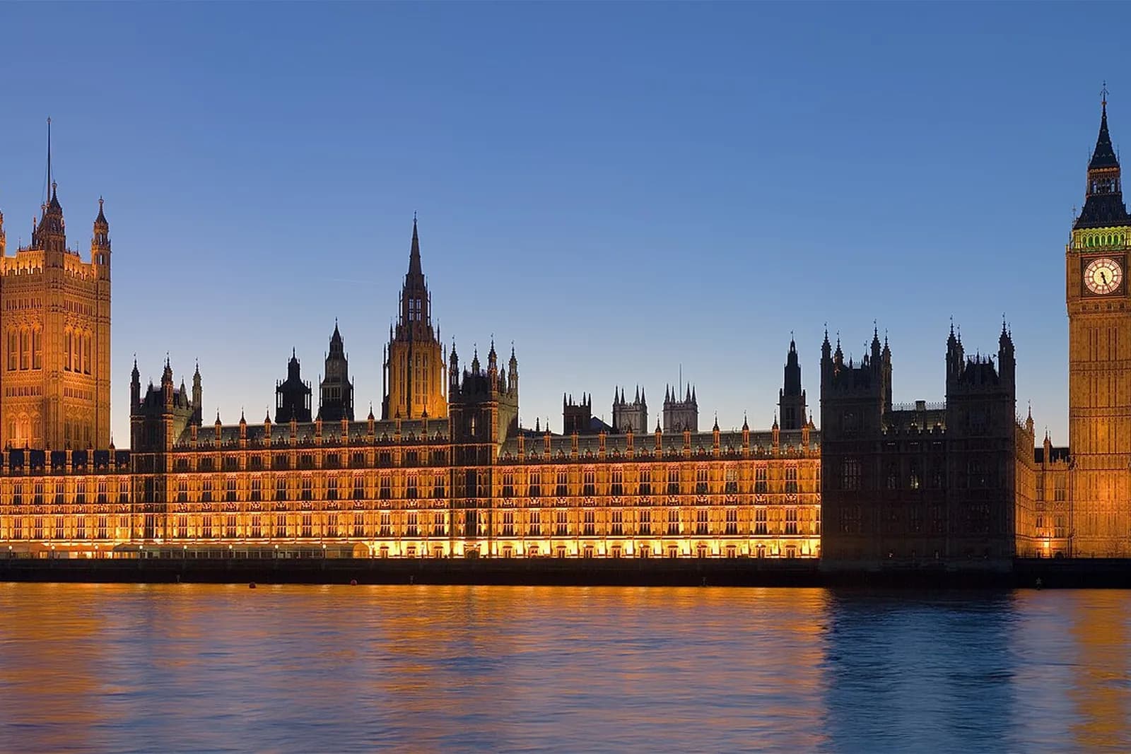 The Palace of Westminster lit up at dusk, reflected in the River Thames