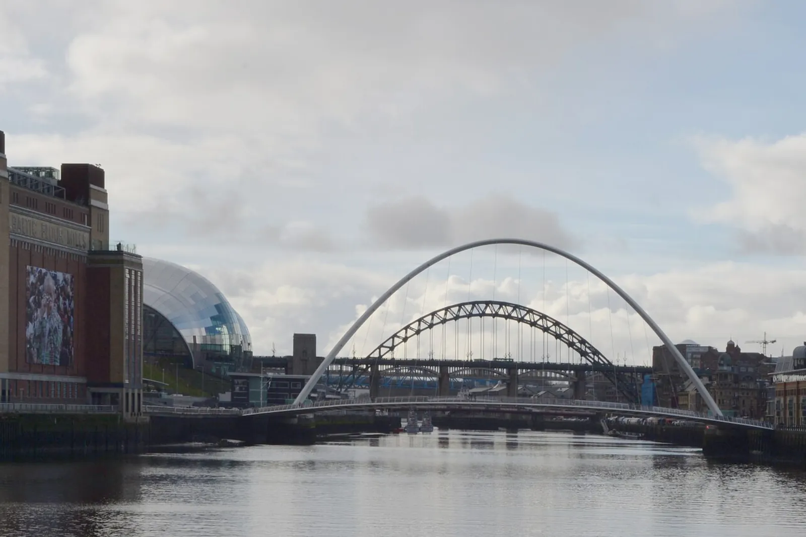 The curved Gateshead Millennium Bridge over the Tyne, with the Tyne Bridge and the Sage behind
