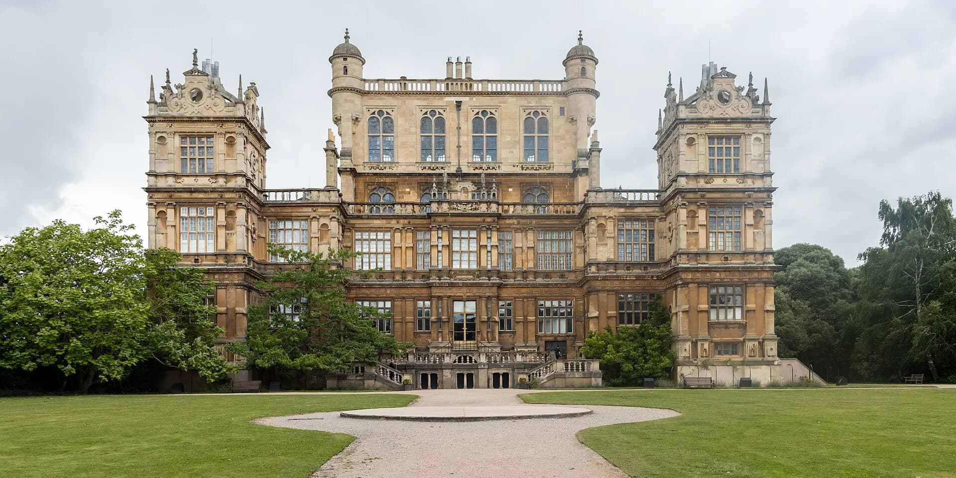 Wollaton Hall, an ornate Elizabethan mansion with corner towers, at the end of a sweeping lawn
