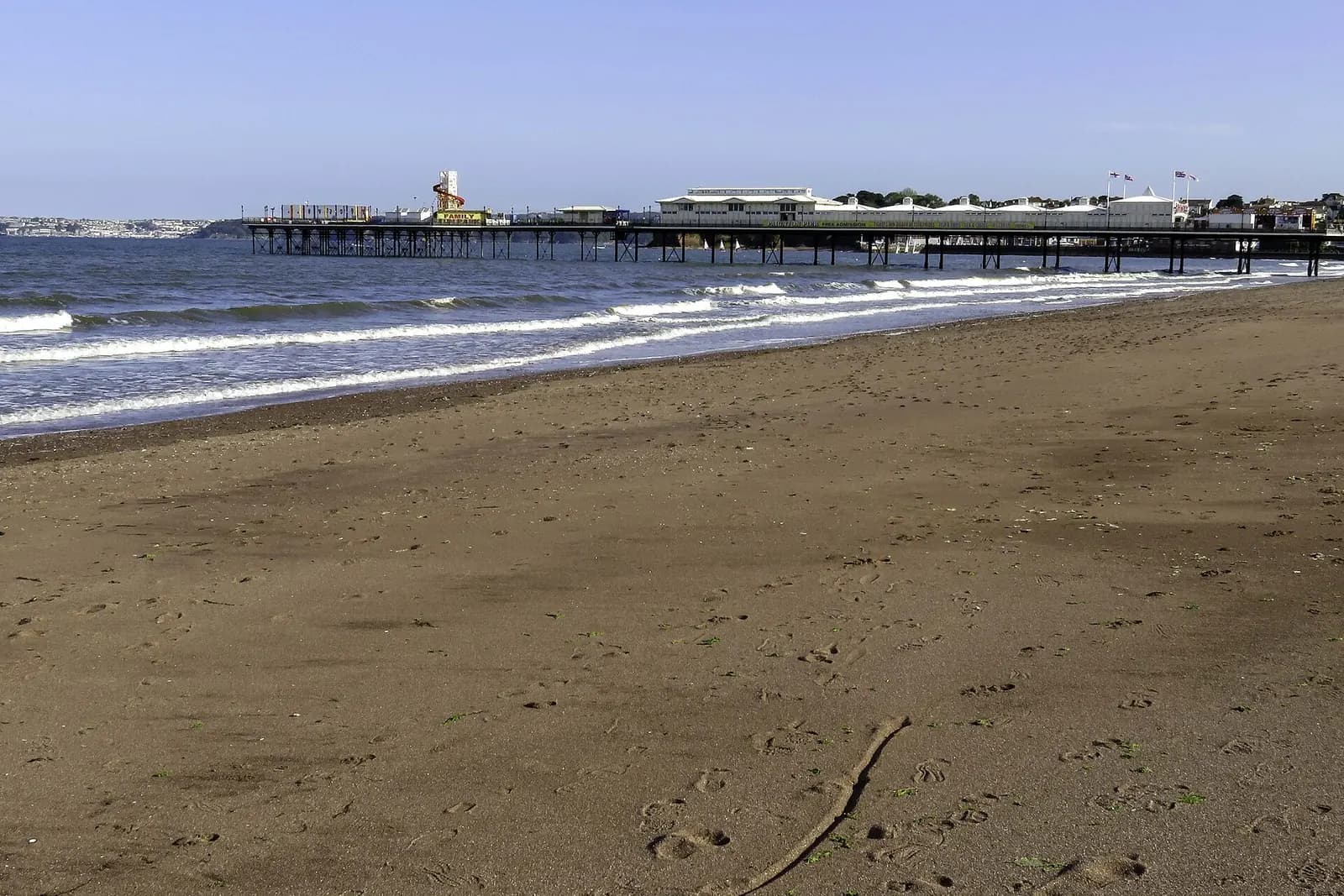 Paignton's sandy beach curving towards the pier on a sunny day