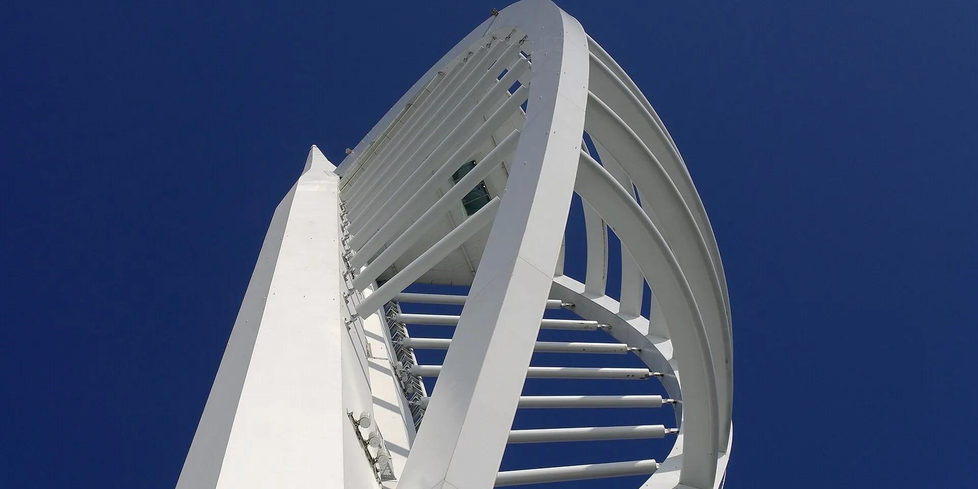 The white sail-shaped Spinnaker Tower against a deep blue sky