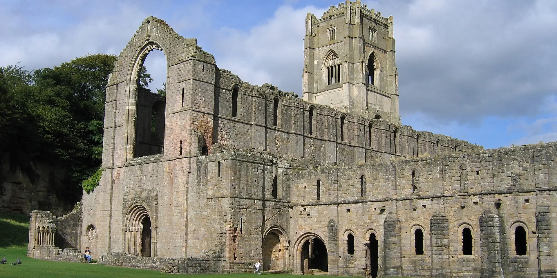 The great ruined church and tower of Fountains Abbey under a blue sky