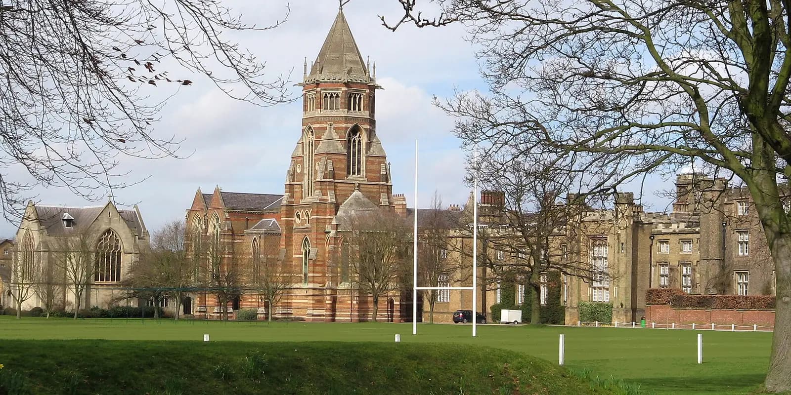 Rugby School's red-brick chapel and buildings beside its playing fields and rugby posts