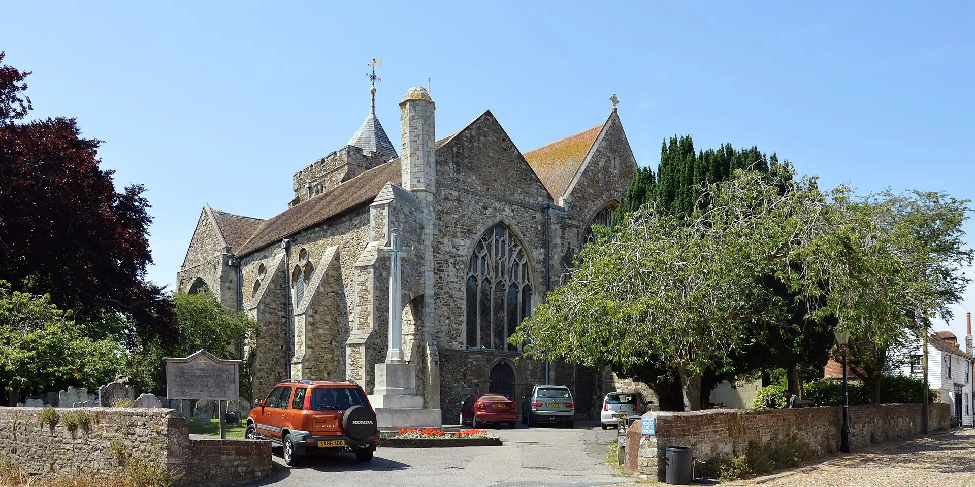 St Mary's Church in Rye, its stone tower and churchyard trees under a blue sky
