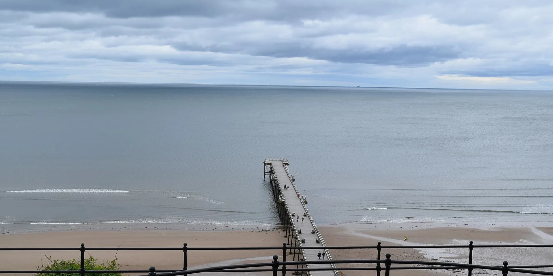 Saltburn Pier reaching out over the sands into a calm grey sea