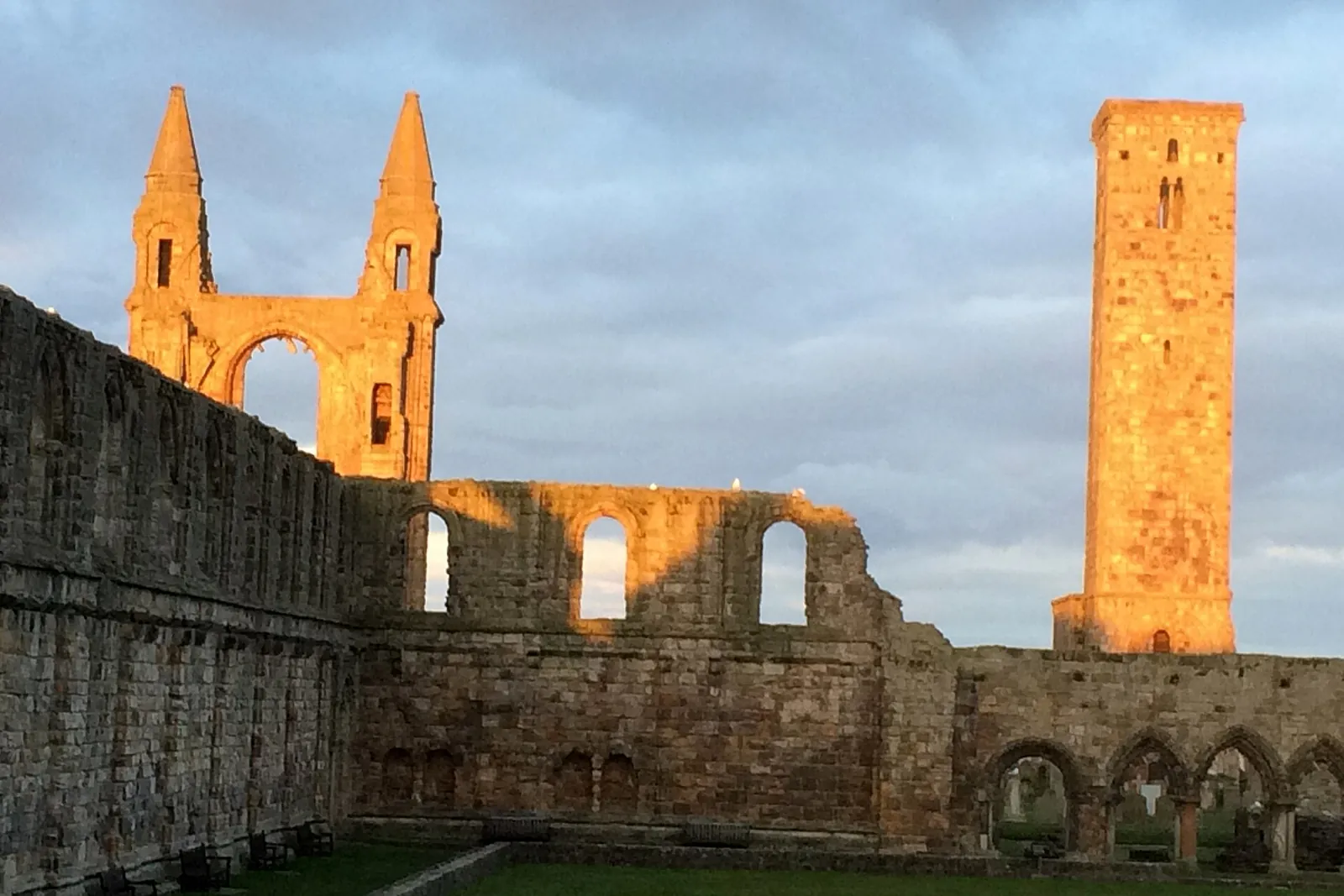 The ruined east gable and St Rule's Tower of St Andrews Cathedral, lit gold by the setting sun