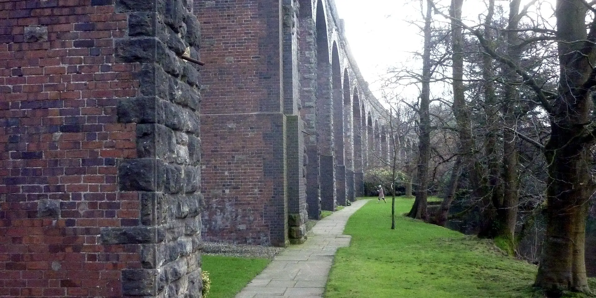 A path beneath the tall stone and brick arches of Charlton Viaduct