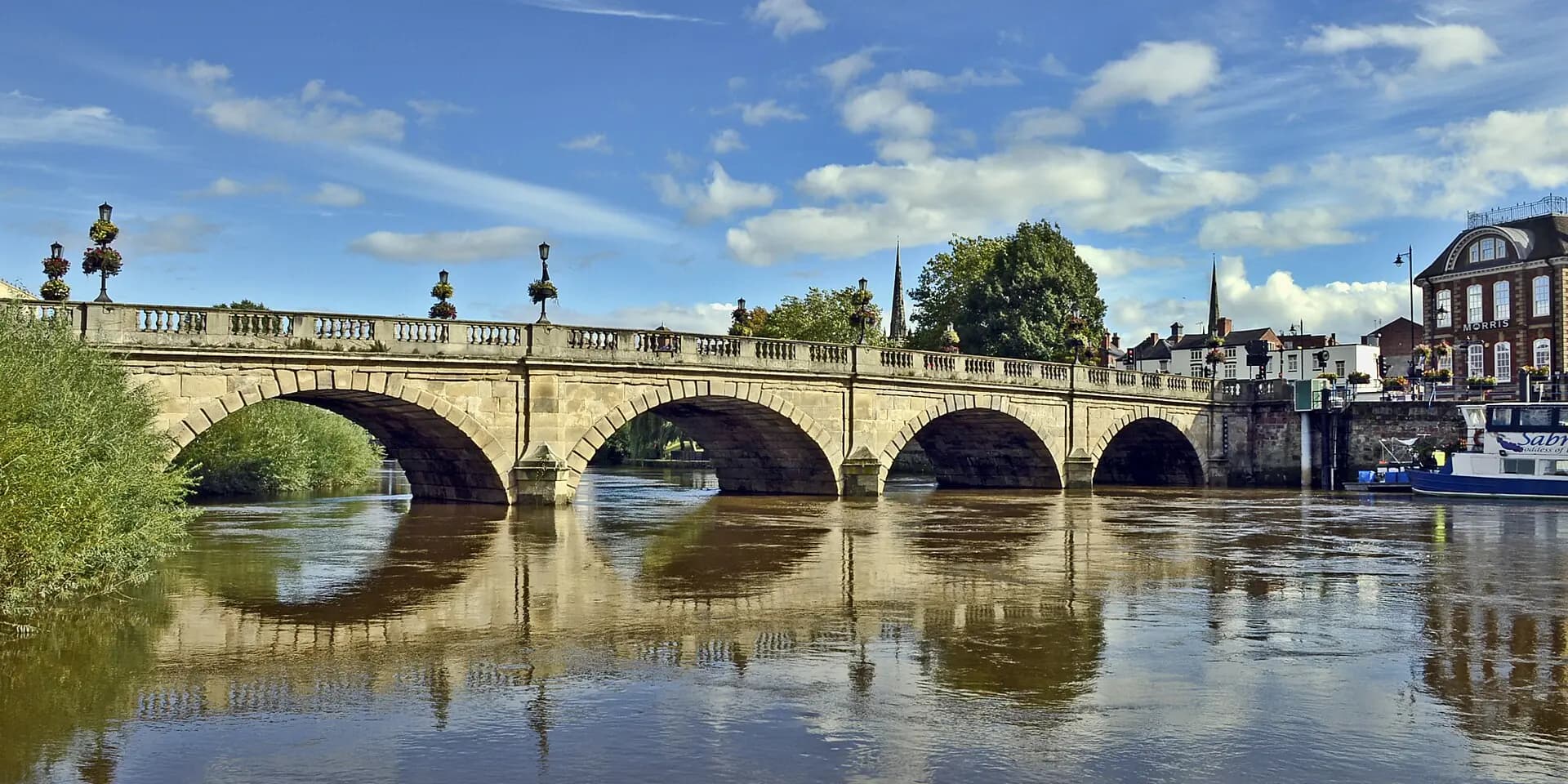 The stone arches of the Welsh Bridge over the River Severn in Shrewsbury, under a blue sky