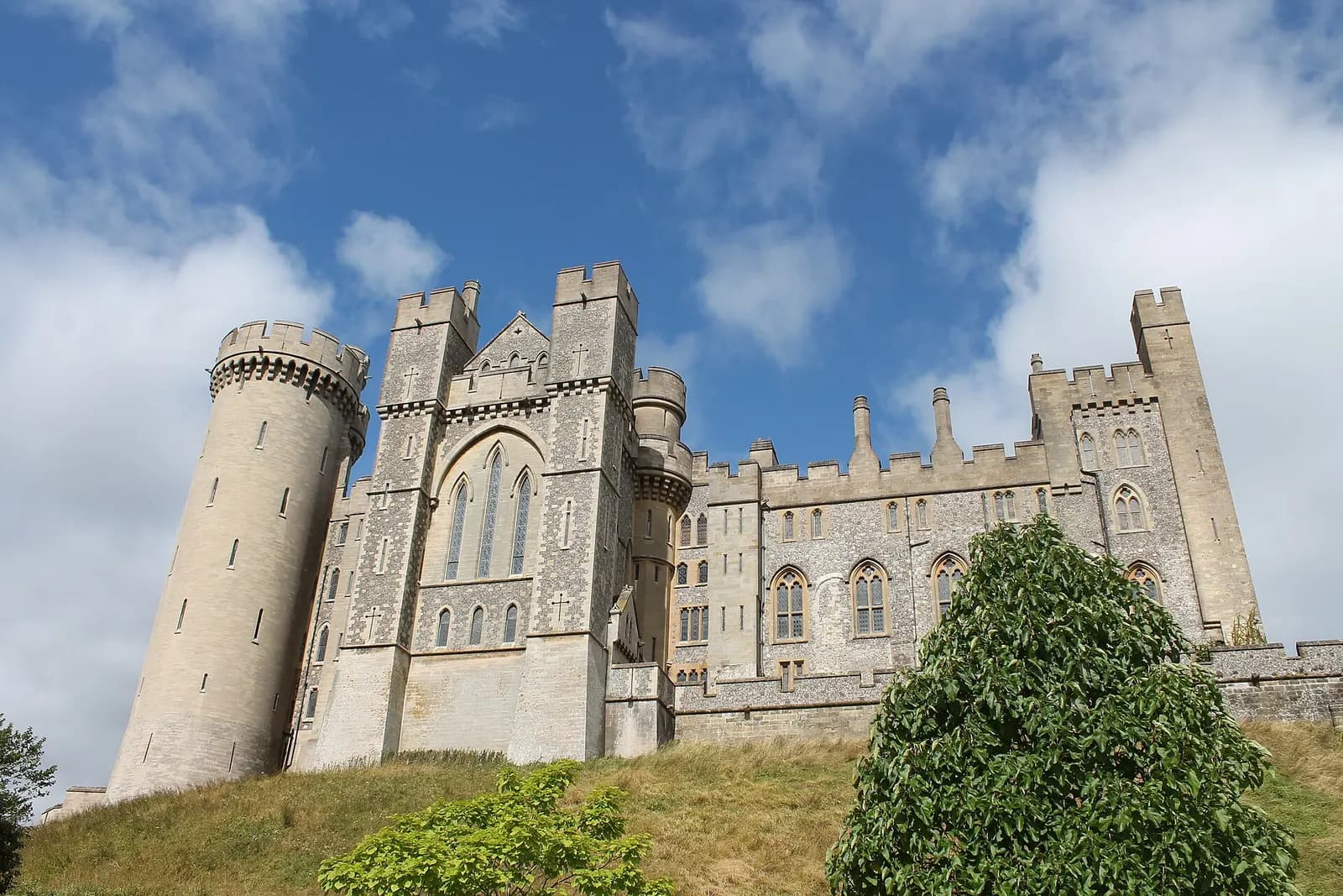 The towers and battlements of Arundel Castle against a blue sky with white clouds