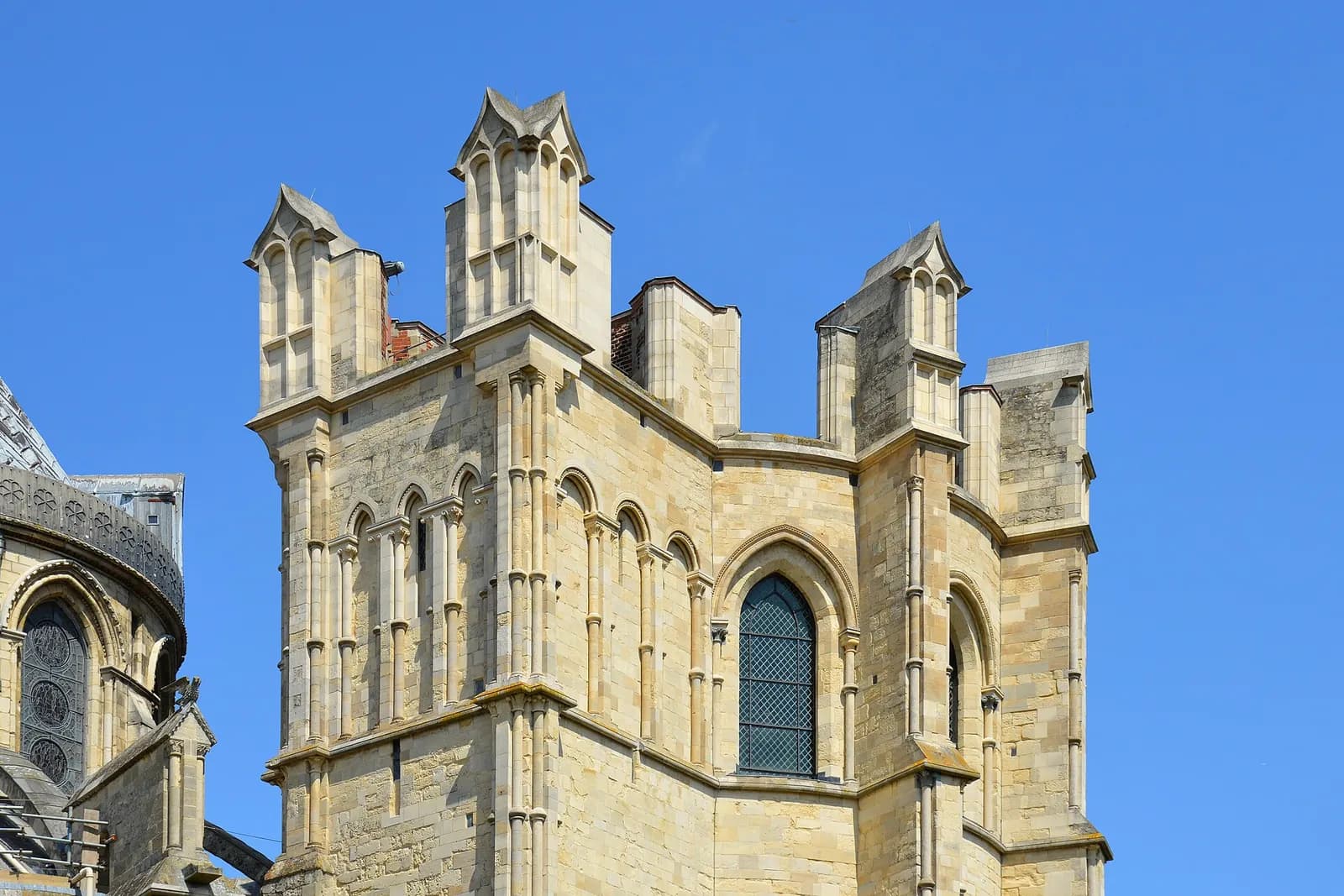 Pinnacled stonework at the top of Canterbury Cathedral against a deep blue sky