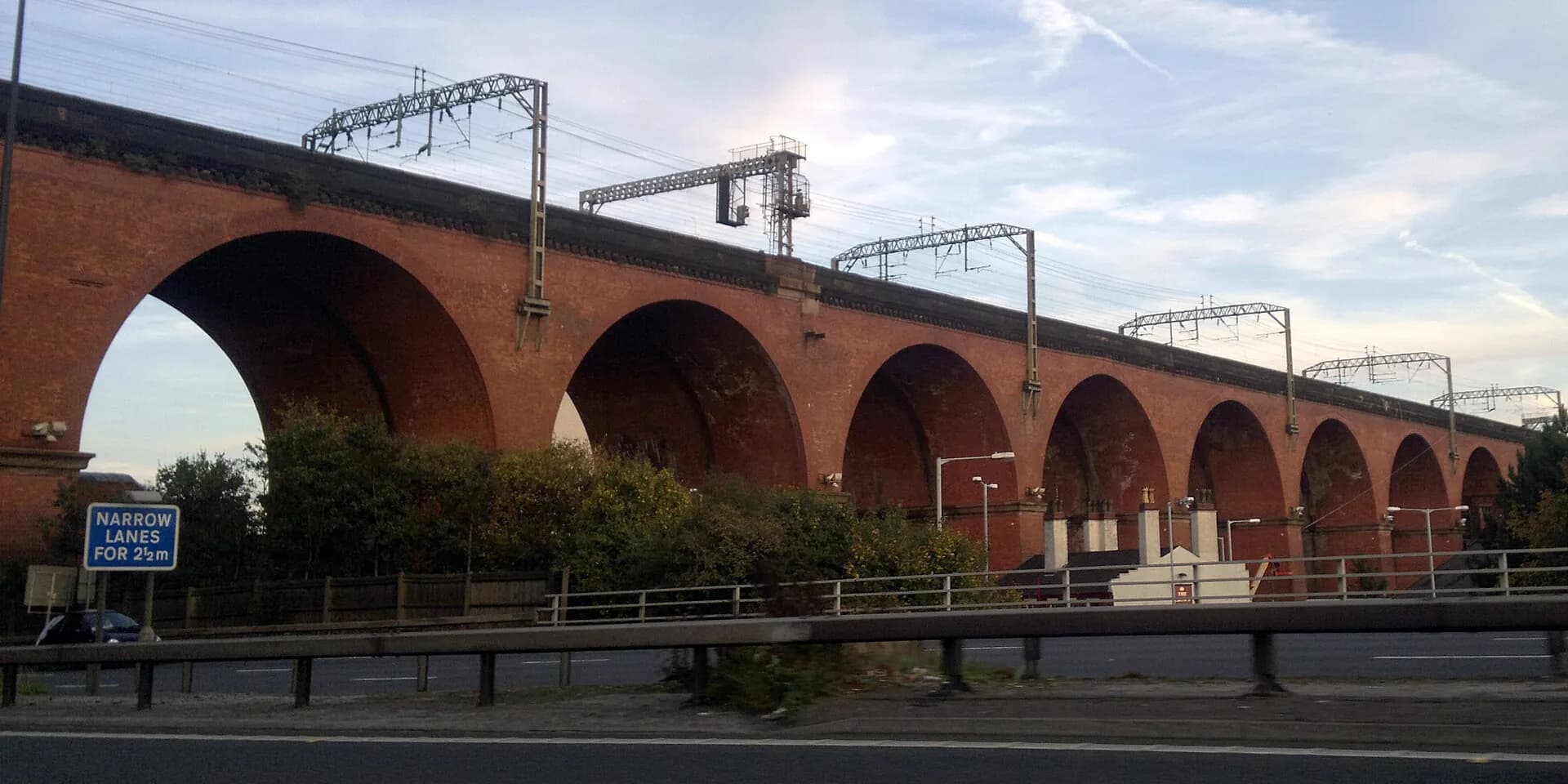 The great red-brick arches of the Stockport Viaduct against a blue sky