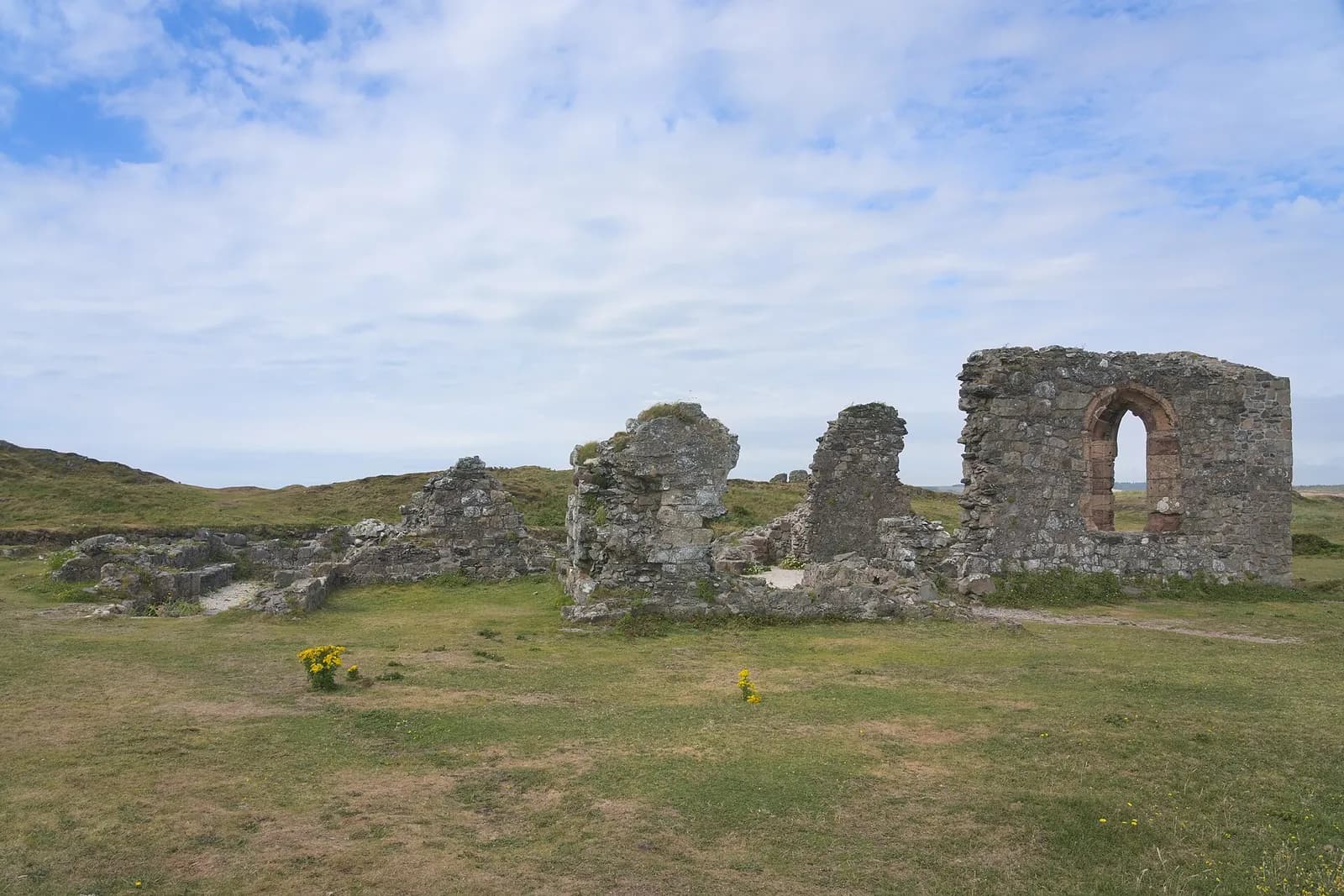 The ruined stone church of St Dwynwen on Llanddwyn Island, among grass and gorse