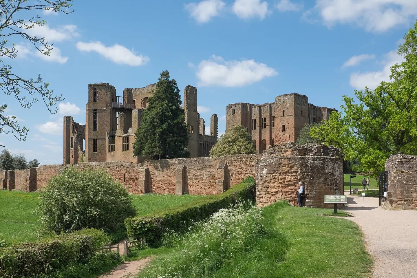 The red sandstone ruins of Kenilworth Castle above green lawns on a sunny day